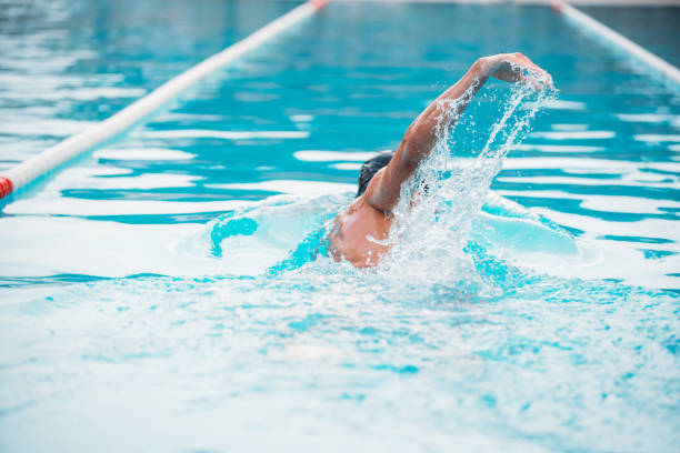 istock Athletic Young man swimming the back crawl in a pool. Swimming competition. 1163863168