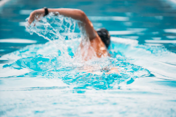 istock Athletic Young man swimming the back crawl in a pool. Swimming competition. 1163863880