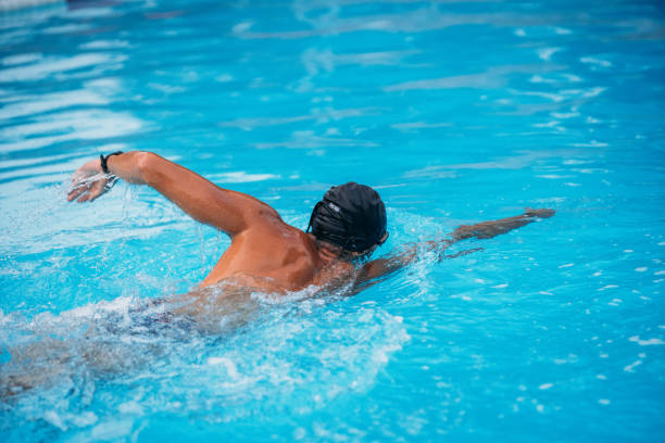 istock Athletic Young man swimming the back crawl in a pool. Swimming competition. 1163863910