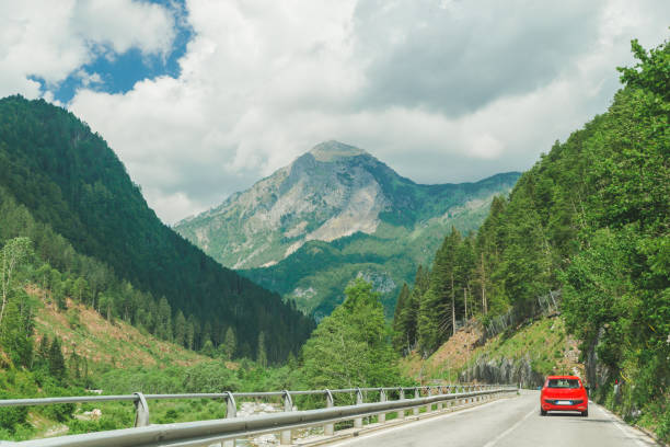 istock small red car on the road through mountains road trip 1163870133