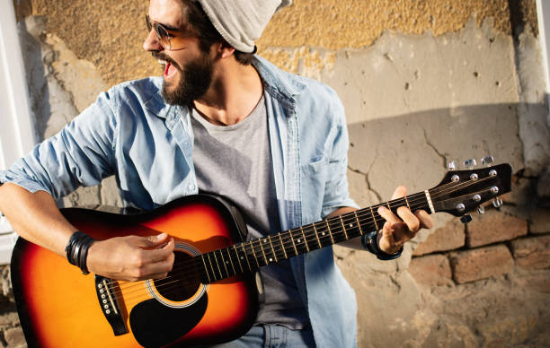 istock Handsome man playing guitar on the street on summer day 1163870968