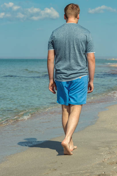 istock Handsome man walking alone on the beach with bare feet. Rest by the beach. 1163871498