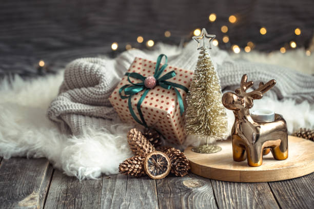 istock Christmas festive background with toy deer with a gift box and Christmas tree, blurred background with golden lights on wooden deck table 1163872567