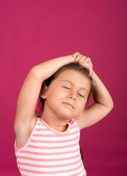 Little girl yawning on pink background