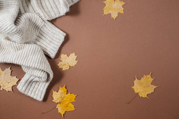 istock Autumn composition. Sweater, autumn maple leaves on brown background. Flat lay, top view, copy space 1163877596