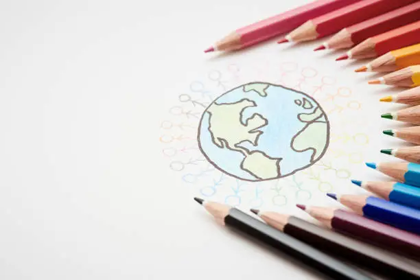 Photo of Multicolored pencils around sketch of Earth surrounded by stick figures