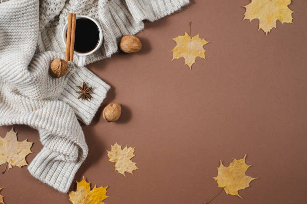 istock Autumn composition. Cup of coffee, nuts, sweater, autumn maple leaves on brown background. Flat lay, top view, copy space 1163879005