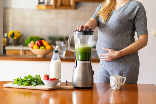 istock Pregnant woman preparing healthy drink at home, using blender 1163882447