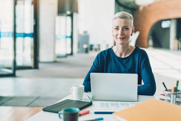 istock Smiling businesswoman sitting in open office space 1163884786