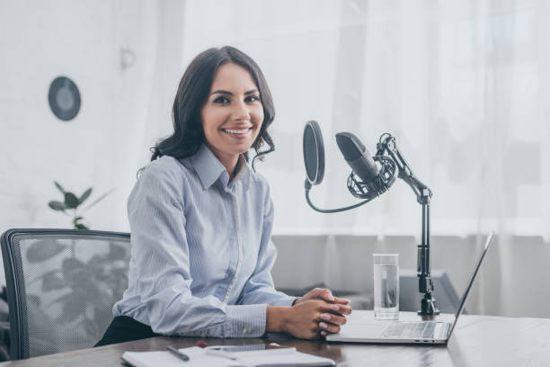 istock cheerful radio host smiling at camera while sitting at workplace near microphone 1163884814