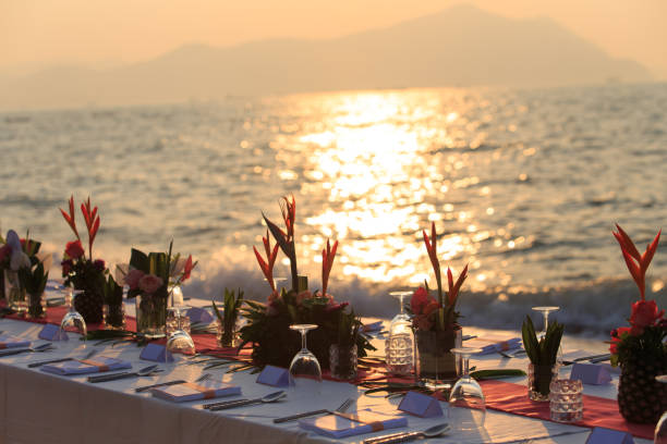 istock Close up dinner table tropical style set on the beach in sunset time Thailand. Beautiful delicate wedding decoration with tropical flowers and fruits. Wedding setting table on the beach. 1163885850
