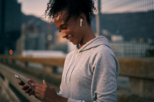 Cropped shot of an attractive young woman wearing earphones and using her cellphone before going for a morning run