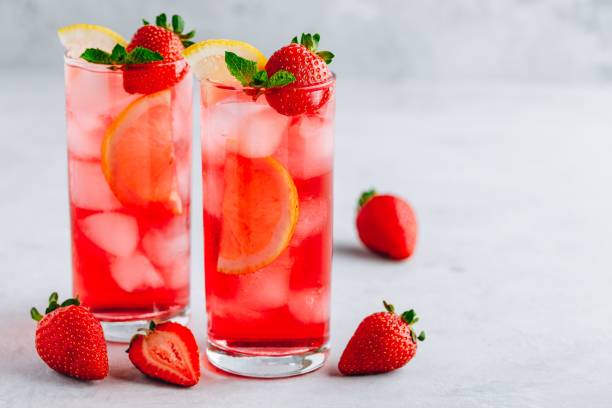 Refreshing Strawberry Mint and lemon Iced Tea or lemonade in glasses Refreshing Strawberry Mint and lemon Iced Tea or lemonade in glasses on a gray stone background pink tea stock pictures, royalty-free photos & images