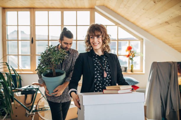 Couple carrying cardboard boxes in new home Man and woman, young couple moving into their new apartment together. tenant stock pictures, royalty-free photos & images