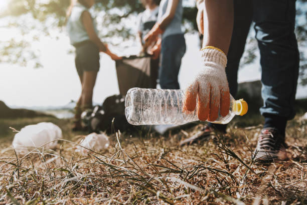istock people picking up garbage and putting it in plastic black bag for cleaning 1163891420