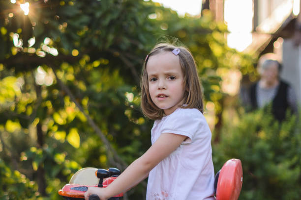 Cute little girl riding tricycle in the yard.