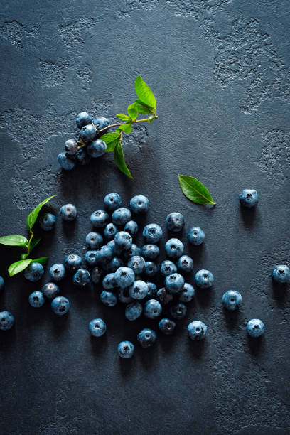 istock Blueberries with leaves on black background, top view 1163892711