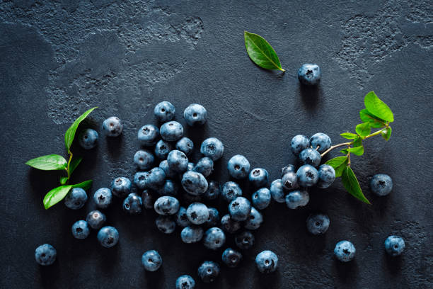 istock Blueberries with leaves on black background, top view 1163892811