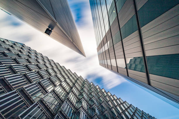abstract low and wide angle view up towards modern business buildings in london's financial district - creative stock image - city of london office building construction architecture imagens e fotografias de stock