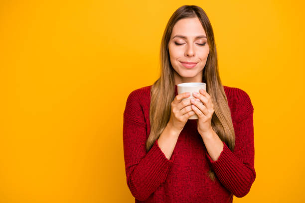 istock Pretty lady holding hot coffee glass overjoyed nice scent wear knitted pullover isolated yellow background 1163894939