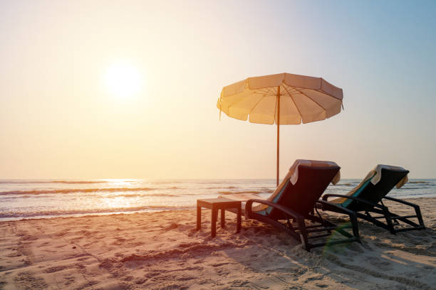 istock Sun umbrellas and chairs on tropical beach with sunset 1163895366