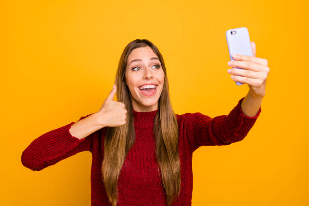 istock Pretty lady with telephone hands making selfies thumb raised up wear knitted pullover isolated yellow background 1163896531