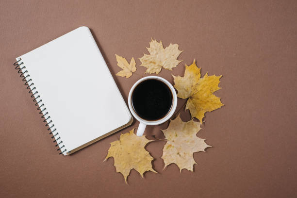 istock Autumn composition. Cup of coffee, notebook, autumn maple leaves on brown background. Flat lay, top view, copy space. 1163897034