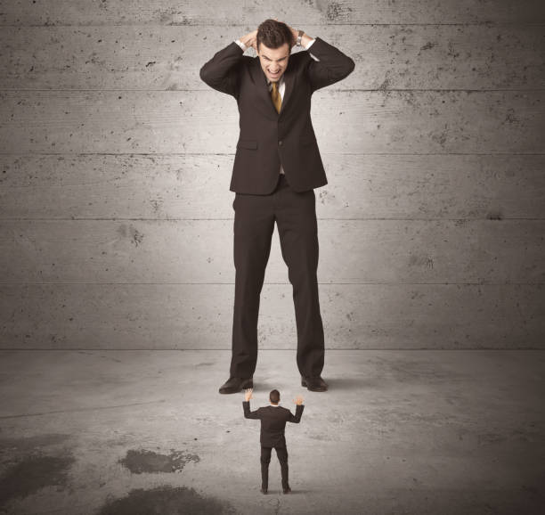 istock Huge business guy looking at small coworker 1163897165