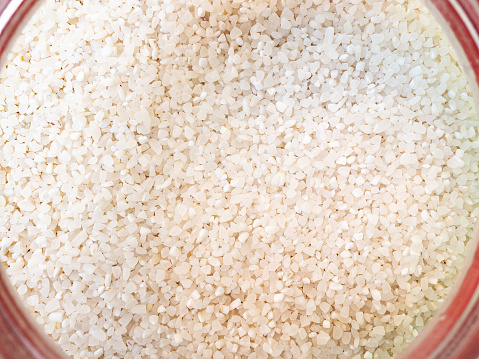 top view of broken rice in pink glass jar close-up