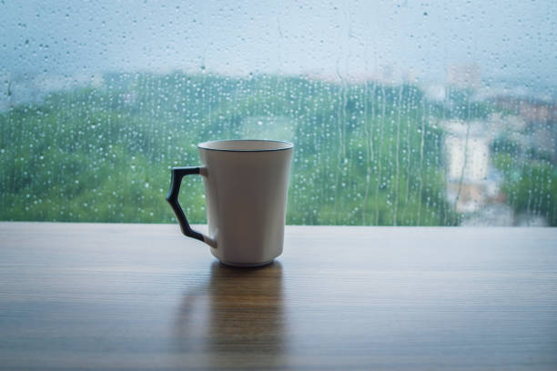 istock Coffee cup on wooden table with rain drops background 1163902763