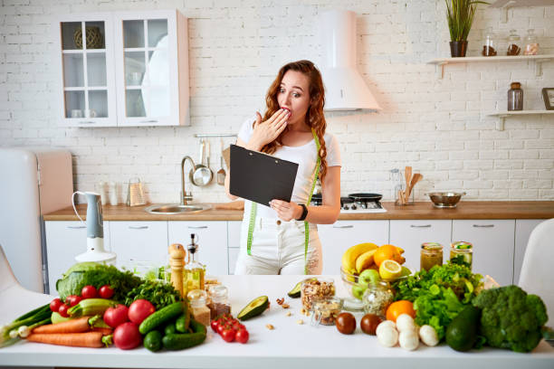 istock Young beautiful woman using tablet while cooking in the modern kitchen. Healthy eating, vitamins, dieting, technology and people concept. Losing Weight 1163902893
