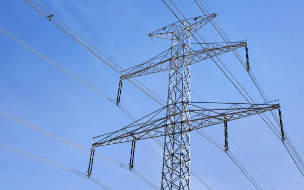 istock Looking up steel electricity pylon with cables, clear sky in background 1163902988