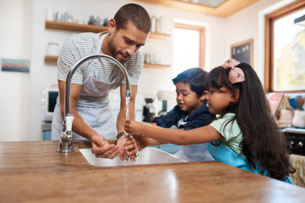 Let's wash those germs away Cropped shot of a man and his two children washing their hands in the kitchen basin kitchen sink photos stock pictures, royalty-free photos & images