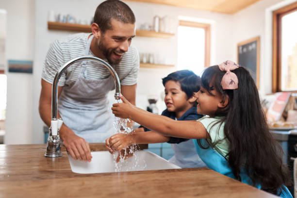 Remember to get in between your fingers Cropped shot of a man and his two children washing their hands in the kitchen basin kitchen sink photos stock pictures, royalty-free photos & images