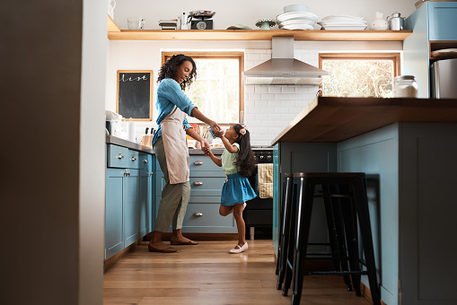 Shot of a young woman dancing with her daughter in the kitchen at home