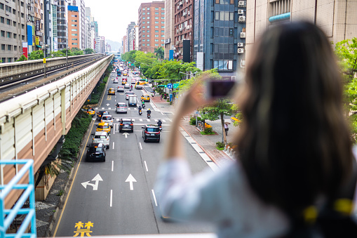 Unrecognizable woman taking photos of road  with traffic in Taipei, rear view