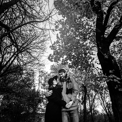 attractive happy luxury couple hugging and holding hands with tender in autumn colorful park