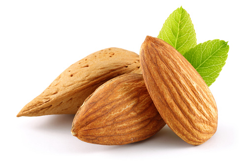 Almonds and green leaves isolated on white background