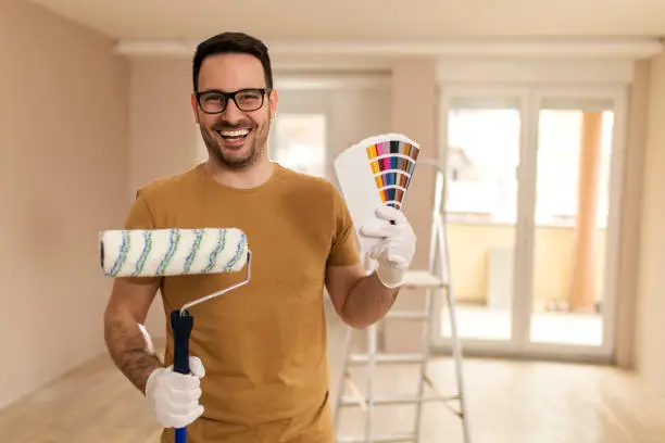 Photo of Young man painting apartment.