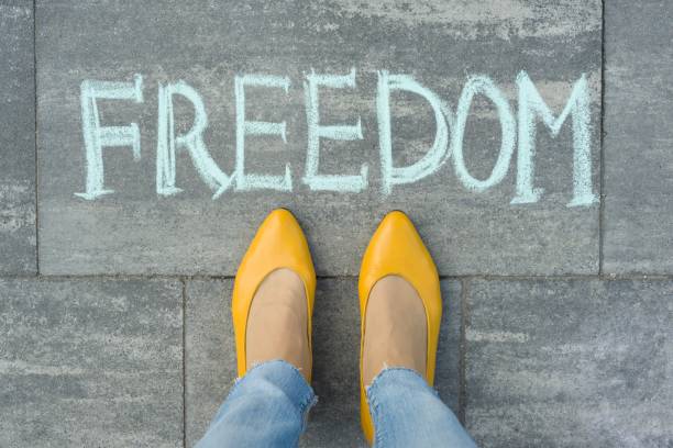 istock Female feet with text freedom written on grey sidewalk 1163912139