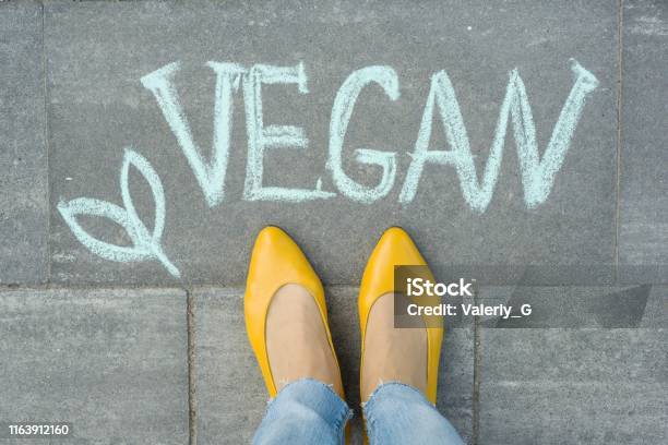 Pies Femeninos Con Texto Vegano Escrito En La Acera Gris Foto de stock y más banco de imágenes de Calzado
