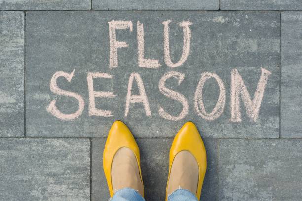 istock Female feet with text flu season written on grey sidewalk 1163912644