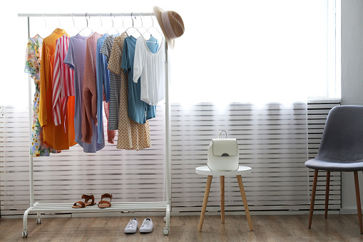 Women's hip clothing store interior concept. Row of different colorful female clothes hanging on rack in hipster fashion show room in shopping mall. Background, copy space for text.