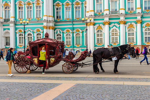 St. Petersburg, Russia - June 26, 2019: Horse-drawn carriage in front of Winter Palace (Hermitage Museum) on Palace Square in Saint Petersburg, Russia