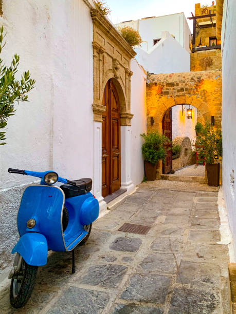Lindos, Rhodes, Greece - June 26th, 2019 : Lindos old town, Rhodes, Greece.  Lindos is a very popular travel destination throughout the year.  It is a medieval community with narrow streets and pathways, both pedal and motorised cycles are a common sight in order to navigate throughout Lindos.