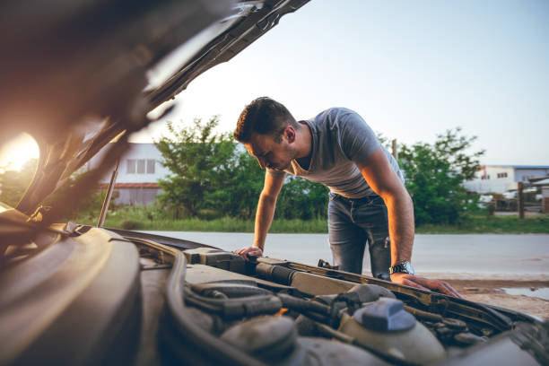 Looking under car hood Young handsome caucasian man looking under car hood. mechanic working under car stock pictures, royalty-free photos & images