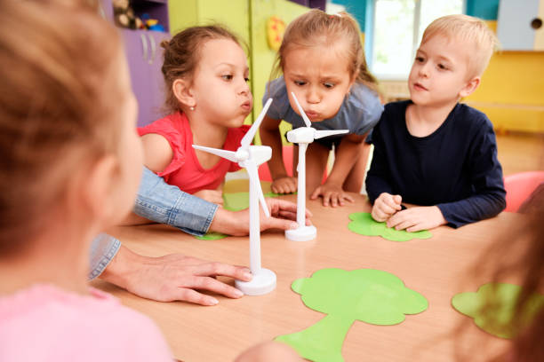 istock Kids blowing model of wind turbine 1163919507