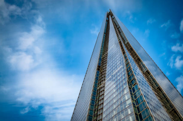 Upward view with a close up n the Shard surrounded by clouds and the blue sky. The Shard is currently the tallest building in the European Union and a London landmark. London, UK - April 28, 2016: Upward view with a close-up n the Shard surrounded by clouds and the blue sky. The Shard is currently the tallest building in the European Union and a London landmark. the shard close up stock pictures, royalty-free photos & images