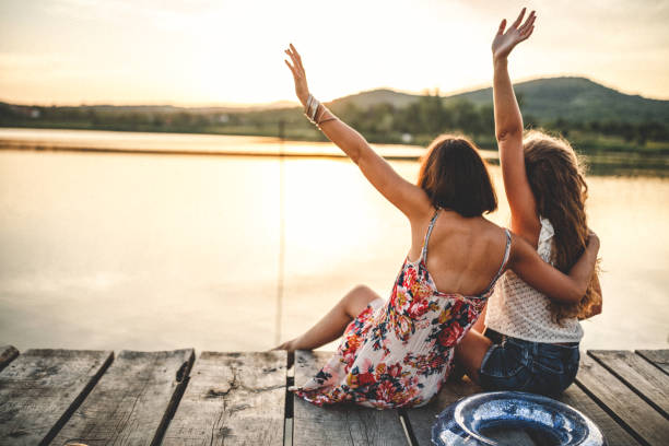 Best friends walking on wooden dock over the lake with inflatable in hands