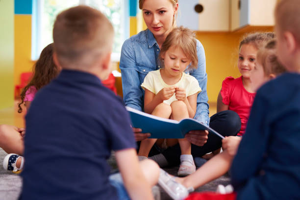 insegnante e bambini che leggono un libro in età prescolare - circle child preschool preschooler foto e immagini stock